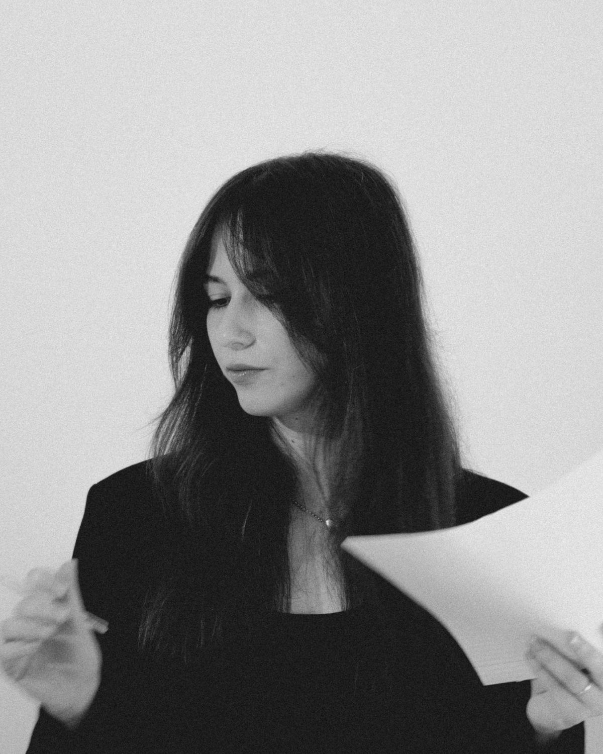 Alexandra, co-founder of Solé, reading through printed pages in the studio, black and white portrait